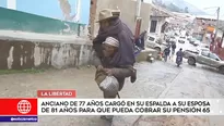 Con una tira de tela sujeta a su esposa para cargarla sobre su espalda