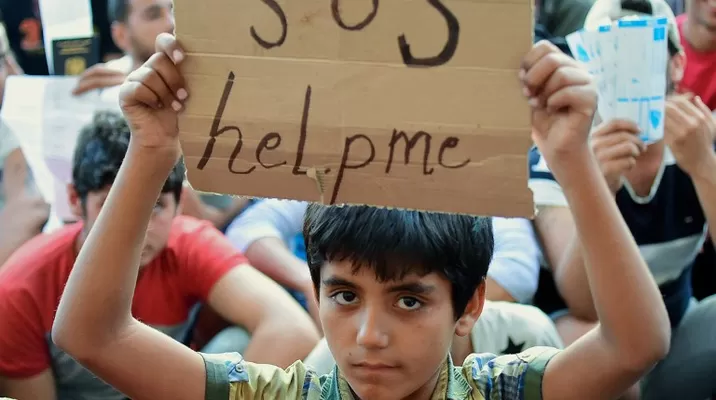 Niño inmigrante sostiene un cartel en el que se lee 'SOS ayúdame' mientras se sienta con otros migrantes en Keleti. (Vía: AFP) Niño inmigrante sostiene un cartel en el que se lee 'SOS ayúdame' mientras se sienta con otros migrantes en Keleti. (Vía: AFP)