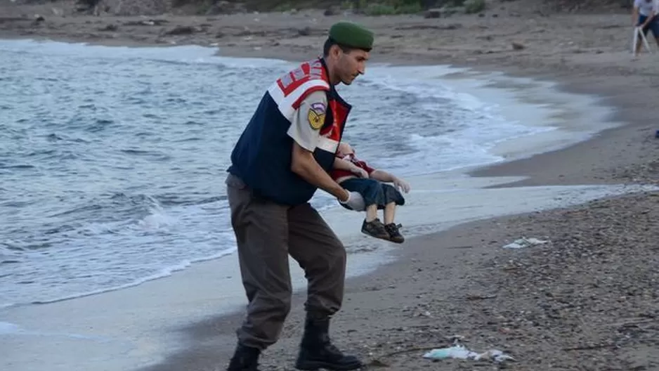 Un oficial levanta el cuerpo de Aylan Kurdi del mar en el centro tur&iacute;stico de Bordrum. (V&iacute;a: The Mirror)