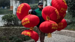 Un trabajador cargando globos de decoración. (Vía: AFP)