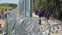 Migrantes y refugiados caminan cerca de la alambrada de p&uacute;as de tres metros de altura puesta por la polic&iacute;a h&uacute;ngara. (V&iacute;a: AFP)