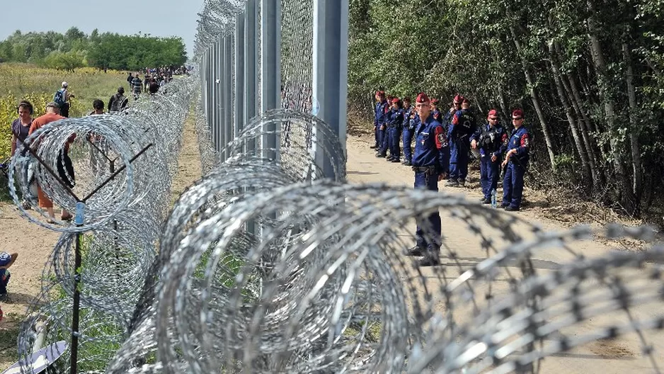 Migrantes y refugiados caminan cerca de la alambrada de p&uacute;as de tres metros de altura puesta por la polic&iacute;a h&uacute;ngara. (V&iacute;a: AFP)