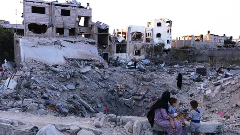 Una madre se sienta junto a sus dos hijos en un cr&aacute;ter donde sol&iacute;a estar su casa. Ahora, totalmente destruida por los ataques israel&iacute;es. (Foto: AFP)