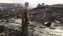 Un hombre pro-ruso permanece con su arma sobre lo que fue la nave de Malaysia Airlines. Foto: REUTERS/Maxim Zmeyev