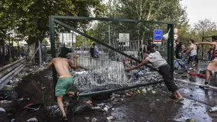 Refugiados intentan remover las vallas de metal en la frontera de Hungr&iacute;a con Serbia. (V&iacute;a: AFP)