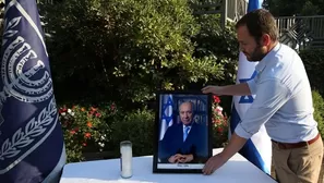 Un trabajador del despacho presidencial israelí coloca una foto del fallecido presidente. (Vía: AFP)