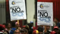 Simpatizantes del partido de Nicolás Maduro sostienen carteles para rechazar la ley de amnistía. (Vía: AFP)