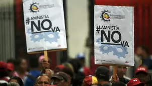 Simpatizantes del partido de Nicolás Maduro sostienen carteles para rechazar la ley de amnistía. (Vía: AFP)