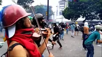 Violinista continúa tocando el himno nacional de Venezuela pese a violenta protesta. Foto: AFP