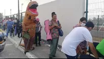 Facebook: Hombre disfrazado de dinosaurio acompaña a su madre a ponerse la vacuna contra COVID-19. Foto: Milenio